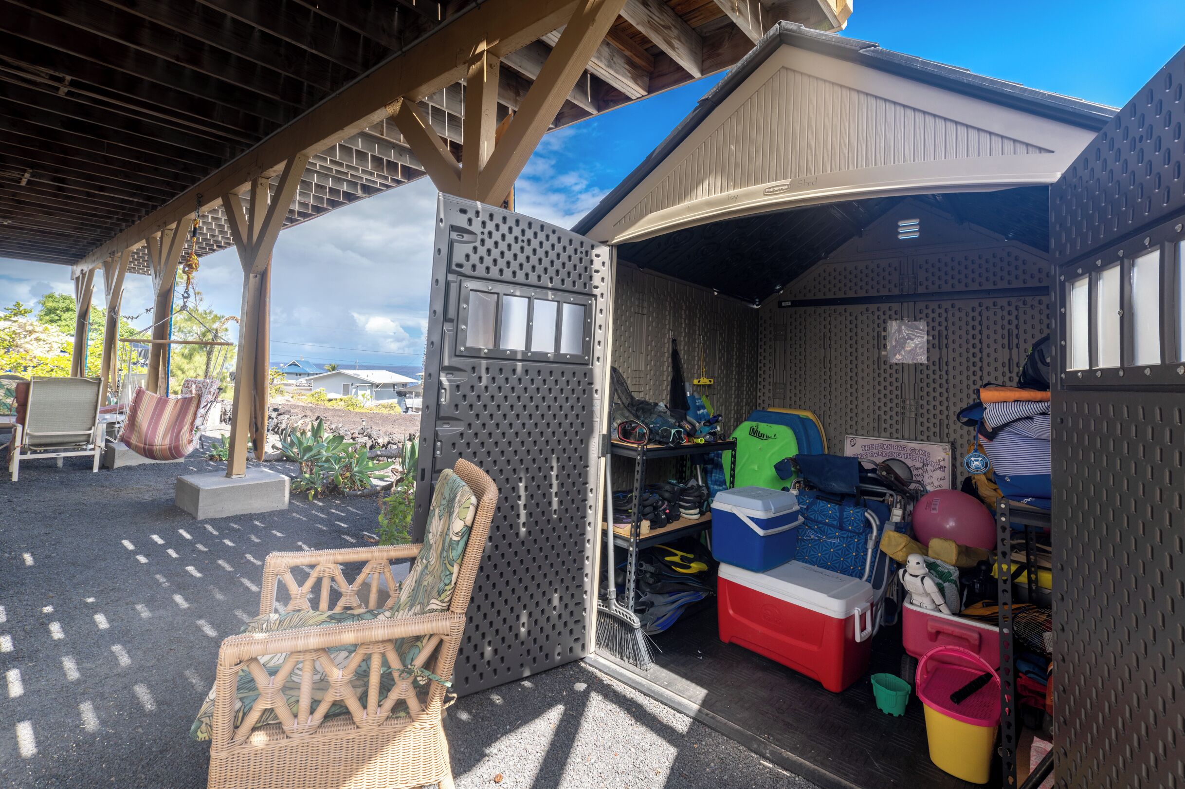Een overdekte buitenruimte met een tuinhuisje waarin verschillende spullen staan.