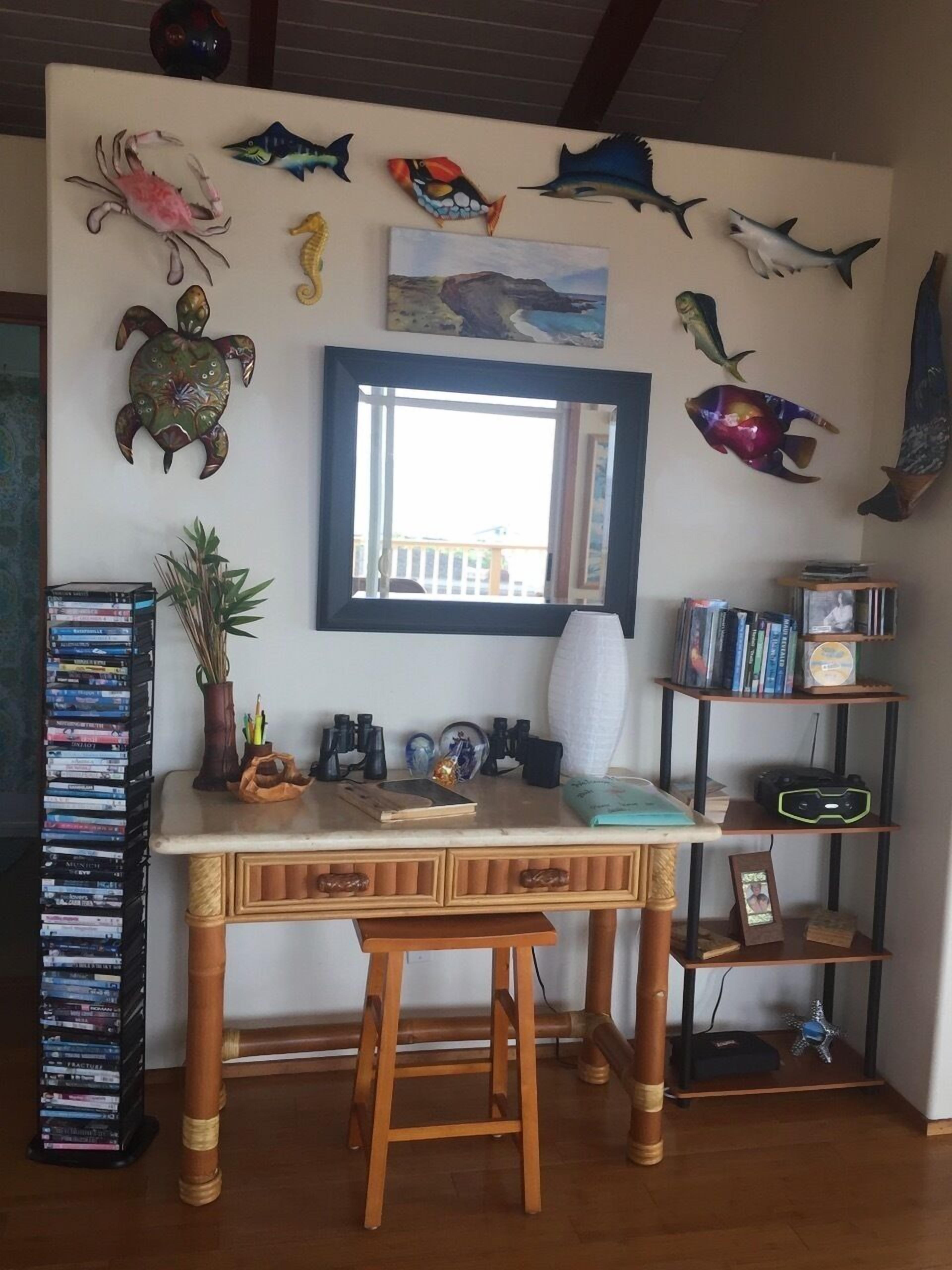 A room with a wooden desk, bookshelves, and decorative fish on the wall.