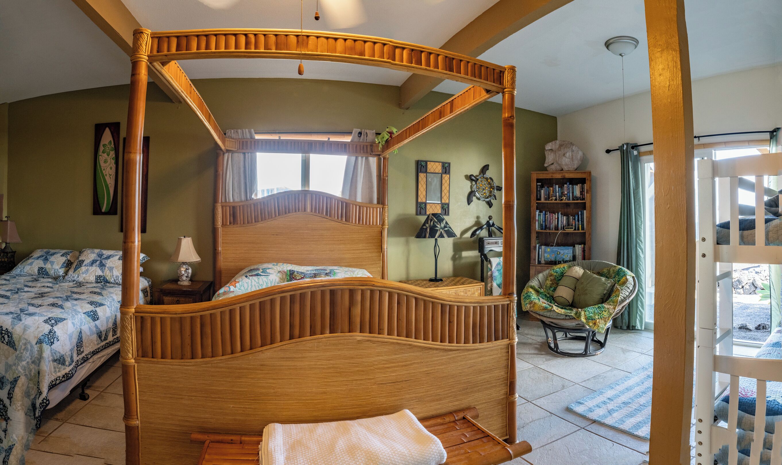 A four-poster bed with a wooden frame and a canopy, a bedside table with a lamp, a chair with a cushion, a bookshelf, and a window with curtains.