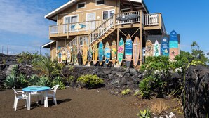 A two-story building with a balcony and a collection of surfboards.