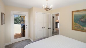 A bedroom with a large bed, a chandelier, a door leading to a balcony, and a painting on the wall. - Affordable Executive Getaway — blocks to Beach and Funk Zone (Santa Barbara)