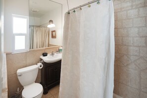A bathroom with a toilet, sink, and mirror.