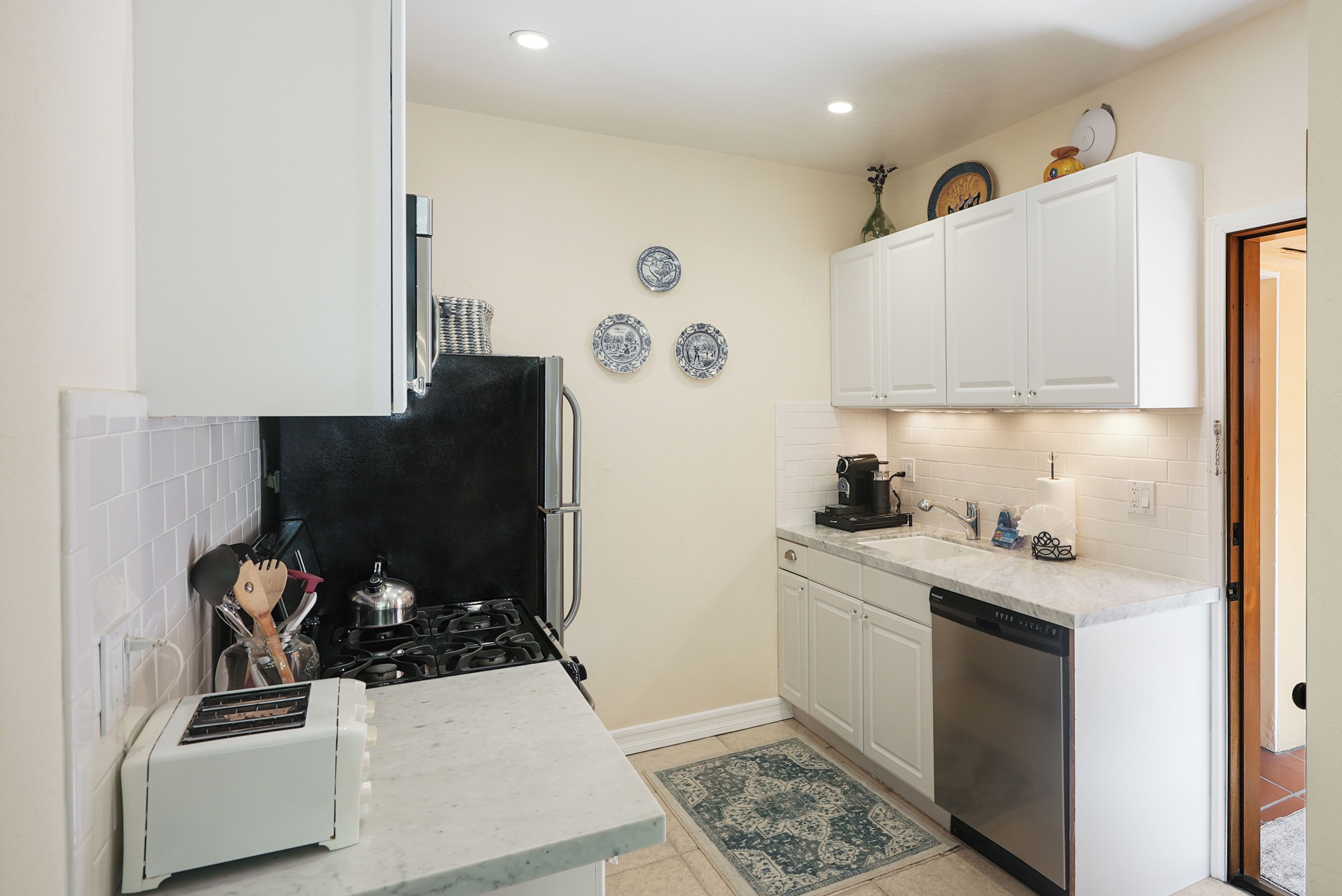 A compact kitchen with white cabinets, a black stove, a dishwasher, and a small countertop.