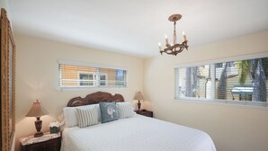 A bedroom with a large bed, two bedside tables, a chandelier, and two windows with blinds. - Affordable Executive Getaway — blocks to Beach and Funk Zone (Santa Barbara)