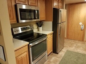 Una cocina con electrodomésticos de acero inoxidable, armarios de madera y un refrigerador.