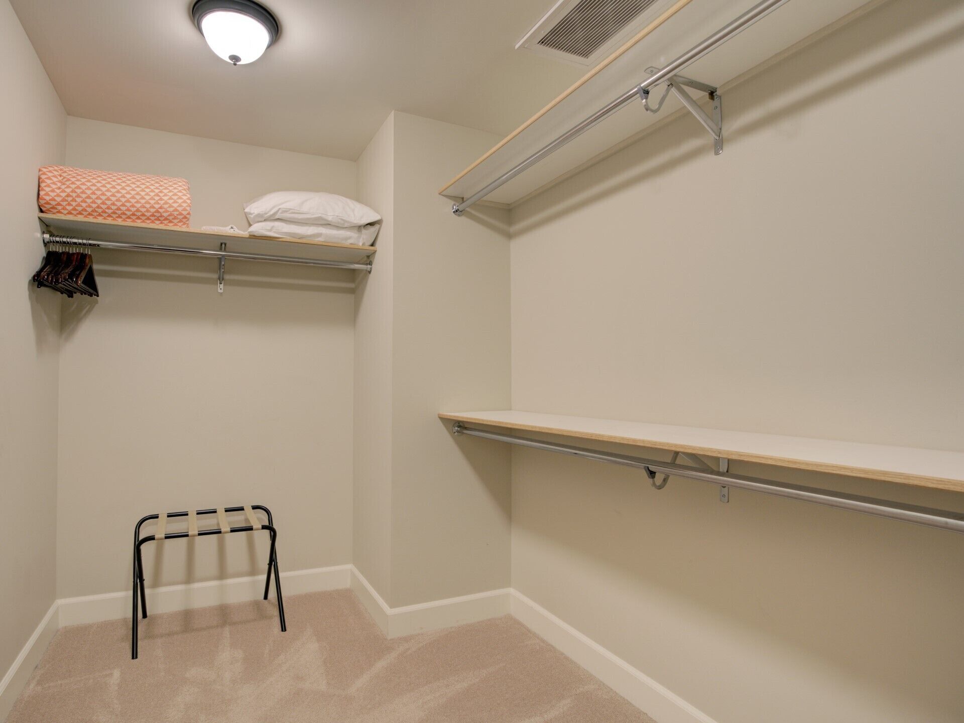 A small, well-lit closet with two shelves, a hanging rack, and a single shelf.