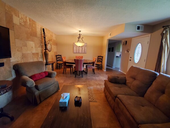 A living room with a sofa, a coffee table, and a dining area with chairs and a table. - Private Guest House - 1800 Sq.ft.-30 Night Minimum (Los Ranchos de Albuquerque)