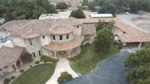Una casa grande de varios pisos con un patio central, rodeada de céspedes y árboles bien cuidados.