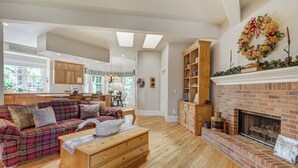 A spacious living room with a fireplace, a plaid sofa, and a wooden dresser. - Broadmoor Estate Summer Rental - Designed for unforgettable family getaways. (Colorado Springs)