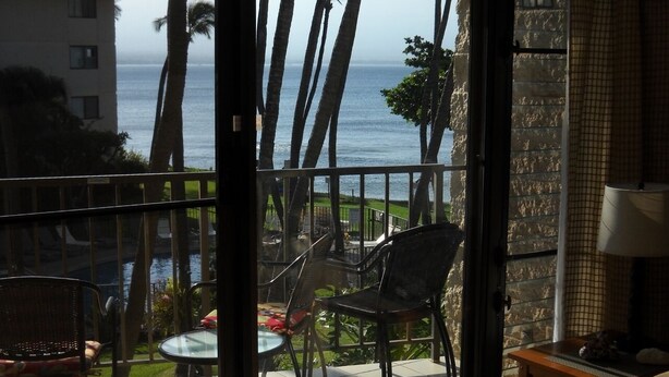 A balcony with a view of the ocean, two chairs, a small table, and a lamp. - 195-295/night, Oceanfront with 2 Master Suites, Fully Stocked, Amazing View!!! (Wailuku)