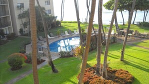 A well-maintained pool area with lounge chairs, surrounded by palm trees and a neatly trimmed lawn. - 195-295/night, Oceanfront with 2 Master Suites, Fully Stocked, Amazing View!!! (Wailuku)