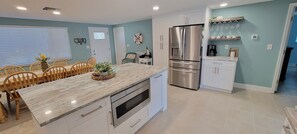 Una cocina moderna con encimera de mármol, electrodomésticos de acero inoxidable y una zona de comedor con sillas de madera.