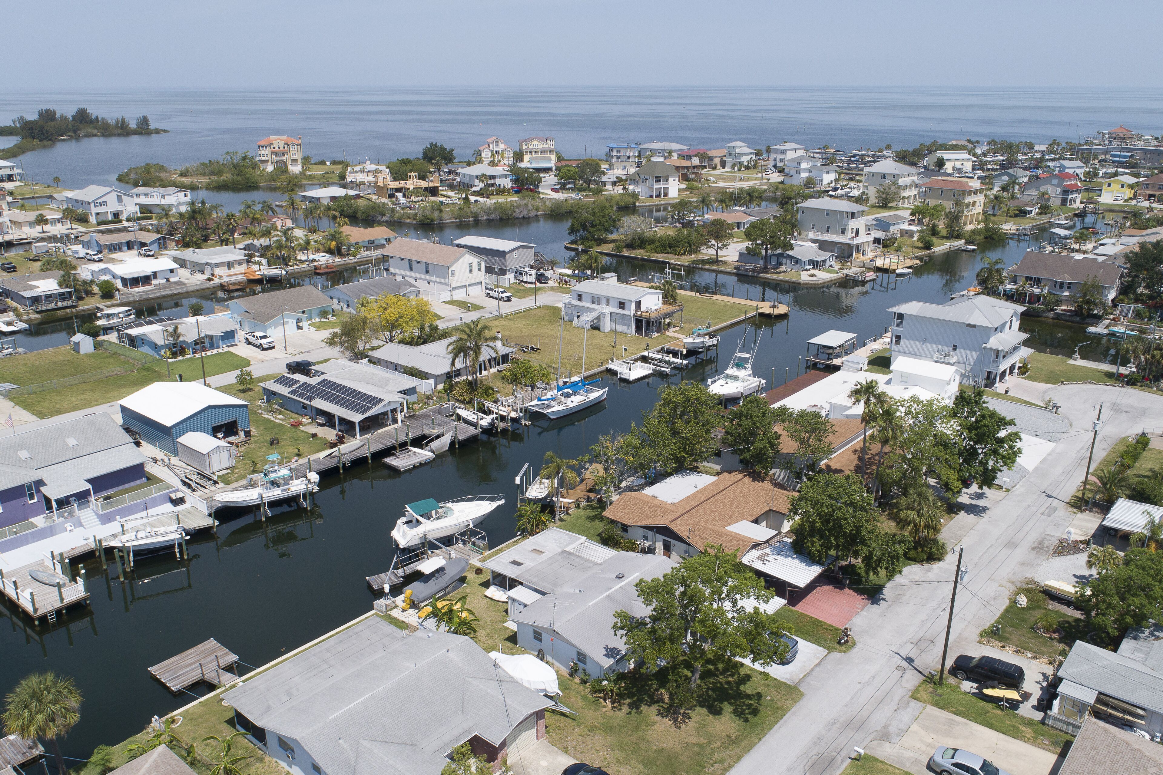 A marina with boats docked, surrounded by residential buildings and a body of water.