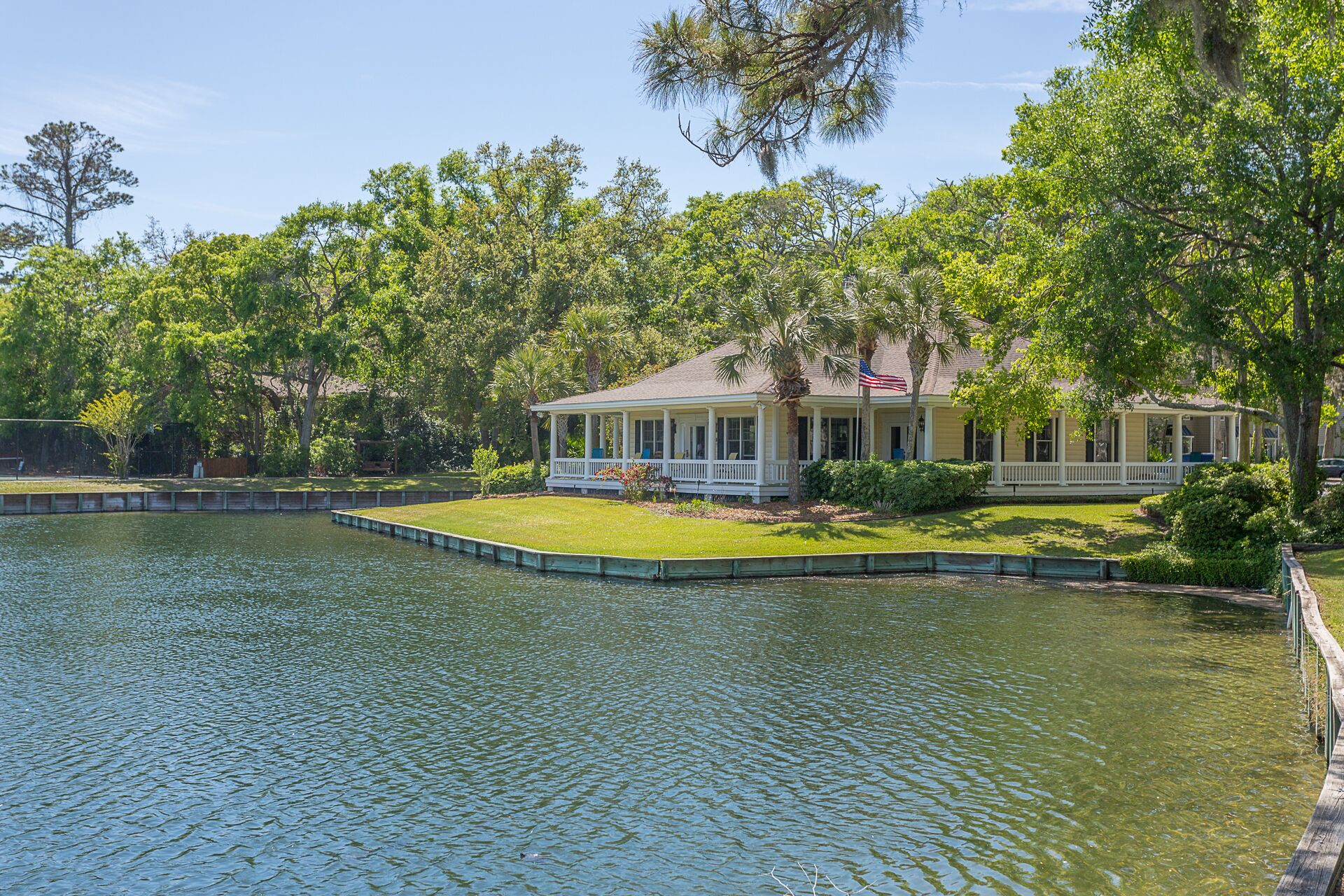 A house with a covered porch, a small lawn, and a body of water in front.