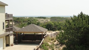 A residential property with a covered patio, a garage, and a view of the surrounding landscape. - Spacious home,saltwater heated pool, game room, volleyball,ocean views & Tennis (Corolla)