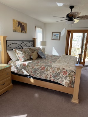 Un dormitorio con cama de madera, ropa de cama floral, ventilador de techo y ventana con persianas.