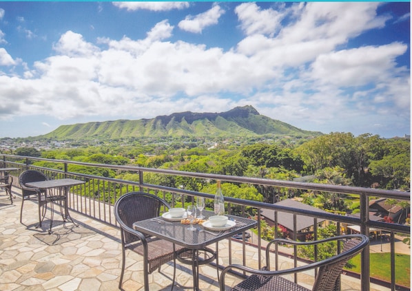Una terraza con mobiliario exterior, vistas a la montaña y suelo de piedra.