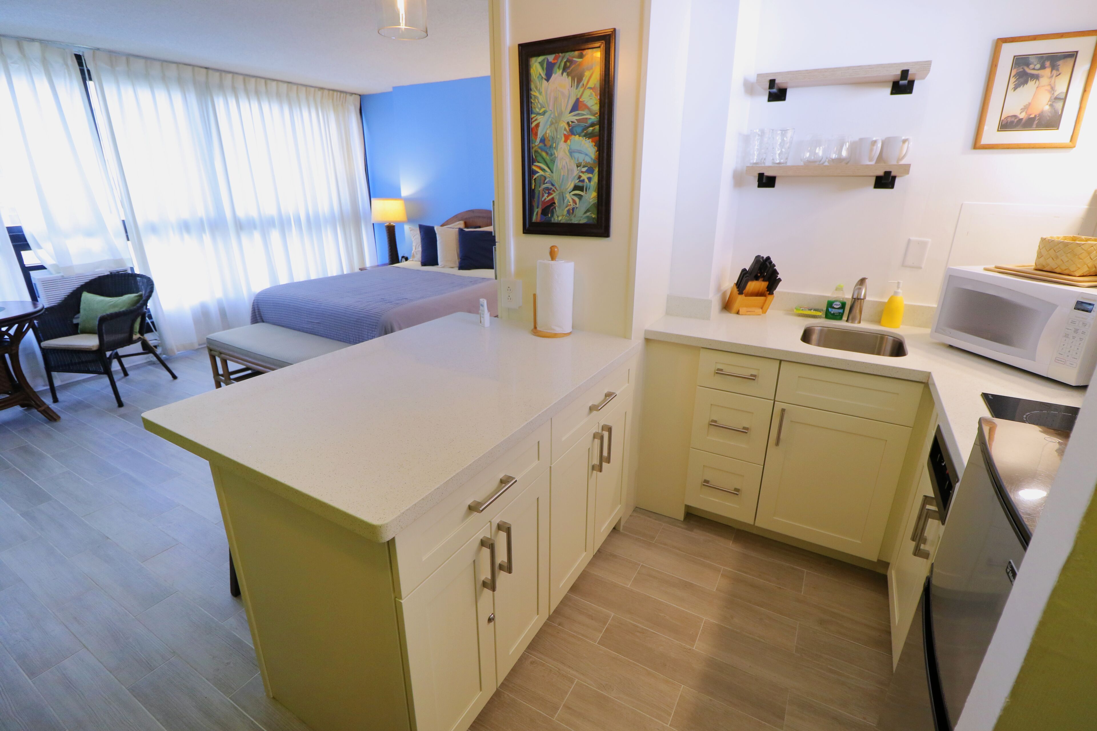 A compact hotel room with a kitchenette, a dining area, and a bed.