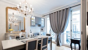 A modern dining area with a chandelier, a large mirror, and a view of the city through a balcony. - Stunning & Spacious in Superb Location with Balcony & Eiffel Views (Paris)
