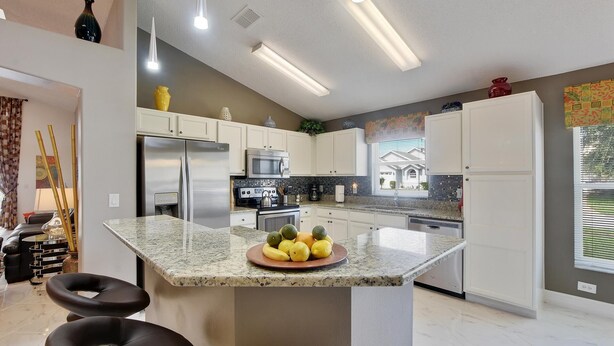 Una cocina moderna con armarios blancos, electrodomésticos de acero inoxidable y encimera de granito.