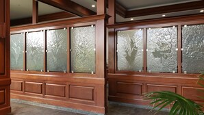 Conjunto de ventanas con marcos de madera y paneles de vidrio satinado con diseños florales en relieve.