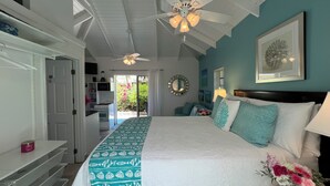 A bedroom with a bed, a ceiling fan, a nightstand, a lamp, and a view of the outdoors.
