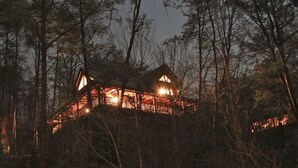 Une cabane aux murs en bois, à plusieurs niveaux, entourée d’arbres.