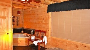 L’intérieur d’un chalet en bois, avec une baignoire en bois, un banc et une fenêtre équipée de stores.