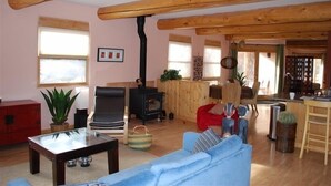A cozy living room with a fireplace, wooden beams, a sofa, and a dining area. - Cozy Adobe with Hot Tub and Fabulous Views in Outdoor Paradise. (Castle Valley)