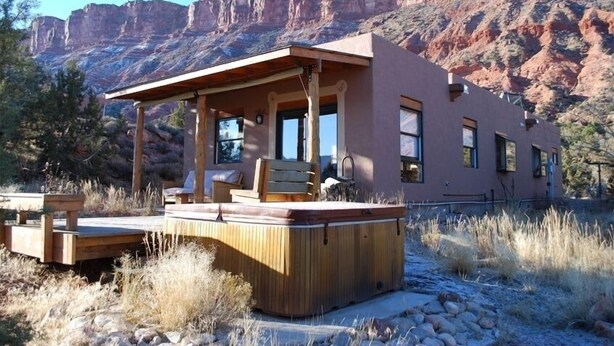 A modern building with a hot tub and outdoor seating area, surrounded by natural landscape. - Cozy Adobe with Hot Tub and Fabulous Views in Outdoor Paradise. (Castle Valley)