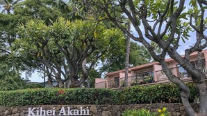 Eine Steinsäule mit der Aufschrift "Kihei Akahi" und ein Gebäude mit einem Balkon.