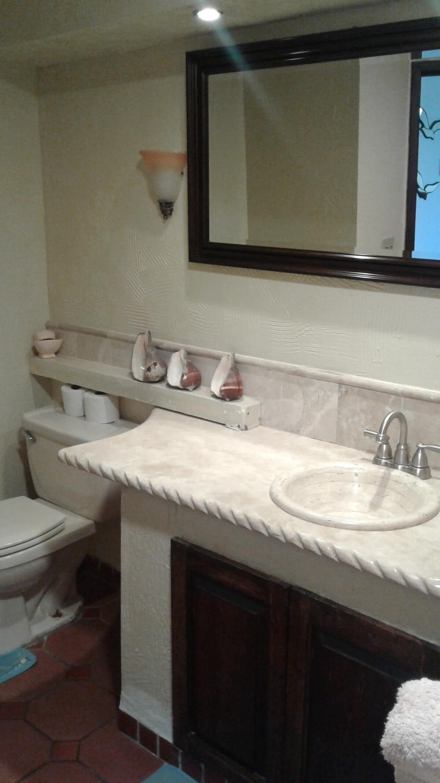 Ein Badezimmer mit Toilette, Waschbecken, Spiegel und Handtuchhalter.