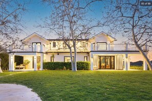 A two-story house with a balcony, a front door, and a well-maintained lawn.
