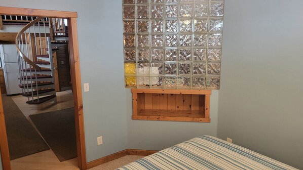 A bedroom with a wooden headboard, a window with a decorative glass panel, and a built-in shelf below the window. - Vacation Rental with pool and access to Bay with dock and launching abilities. (Sterling)