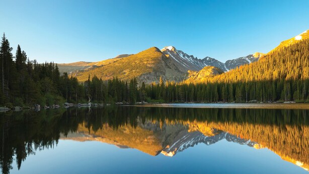 A calm lake reflecting mountains and dense forest. - Downtown Luxury Loft- Enjoy the Mountains in the Heart of Downtown Estes Park (Estes Park)