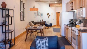 A modern kitchen with white appliances, a dining area with a wooden table and chairs, and a living room with a blue sofa and patterned rug. - Downtown Luxury Loft- Enjoy the Mountains in the Heart of Downtown Estes Park (Estes Park)