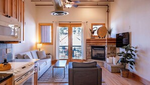 A modern living room with a fireplace, a sofa, a dining table, and a kitchen area with a stove. - Downtown Luxury Loft- Enjoy the Mountains in the Heart of Downtown Estes Park (Estes Park)