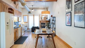 A modern kitchen with wooden cabinets, a dining table set for four, and a fireplace. - Downtown Luxury Loft- Enjoy the Mountains in the Heart of Downtown Estes Park (Estes Park)