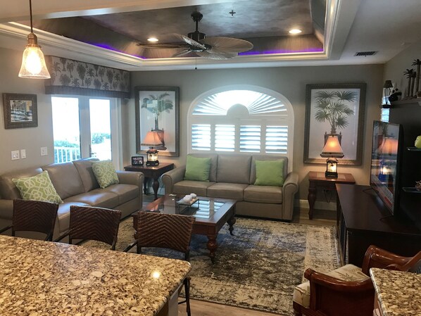 A spacious living room with a large sofa, a coffee table, and a dining area with a granite table.