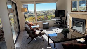 A living room with a sofa, armchairs, a coffee table, a TV, a fireplace, and large windows with a view of the outdoors. - Pajaro Dunes Vacation Home on Epic Private Beach for family or Romantic Getaway (Watsonville)