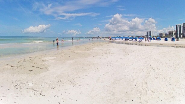 A wide sandy beach with a clear sky and distant buildings. - Upscale Top-Floor Condo W/Gulf View, Sugary Sand Beach (Fort Myers Beach)