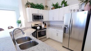 A modern kitchen with granite countertops, stainless steel appliances, and white cabinetry. - Upscale Top-Floor Condo W/Gulf View, Sugary Sand Beach (Fort Myers Beach)