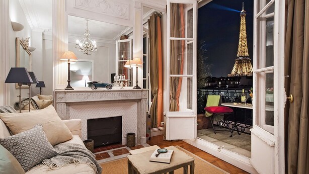 A cozy living room with a fireplace, a sofa, and a view of the Eiffel Tower through an open door. - Dream-Come-True With Breathtaking Eiffel & Paris Views + Terrace (Paris)