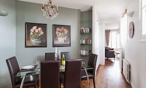 A dining area with a glass table, dark chairs, a chandelier, and two framed floral paintings on the wall. - Dream-Come-True With Breathtaking Eiffel & Paris Views + Terrace (Paris)
