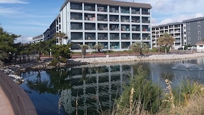 Un hotel de varios pisos con balcones, un cuerpo de agua en primer plano y un cielo despejado.