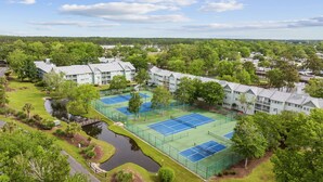 Zona residencial con varios edificios de apartamentos, una cancha de tenis y un pequeño estanque.