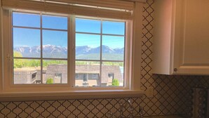 A kitchen with a large window, a sink, and patterned backsplash. - Pink Fridge! Condo in Downtown Whitefish (Whitefish)