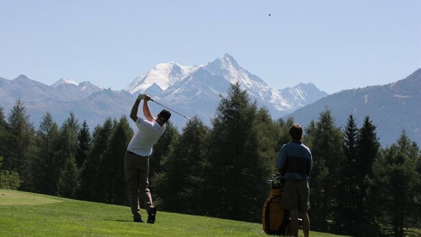 Two people on a golf course with a mountainous backdrop. - Pink Fridge! Condo in Downtown Whitefish (Whitefish)