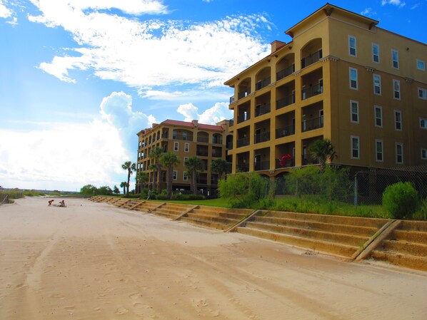 Un hôtel à plusieurs étages doté de balcons, situé juste à côté d’une plage de sable.