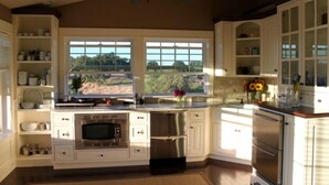 A kitchen with white cabinets, a stainless steel refrigerator, an oven, and a microwave. There are windows with a view of greenery outside. - AUBURN COTTAGE POOL HOUSE, SPA AND GROUNDS G & Christmas Now Open 5 day min (Auburn)